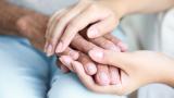 Two people holding hands in a comforting way.